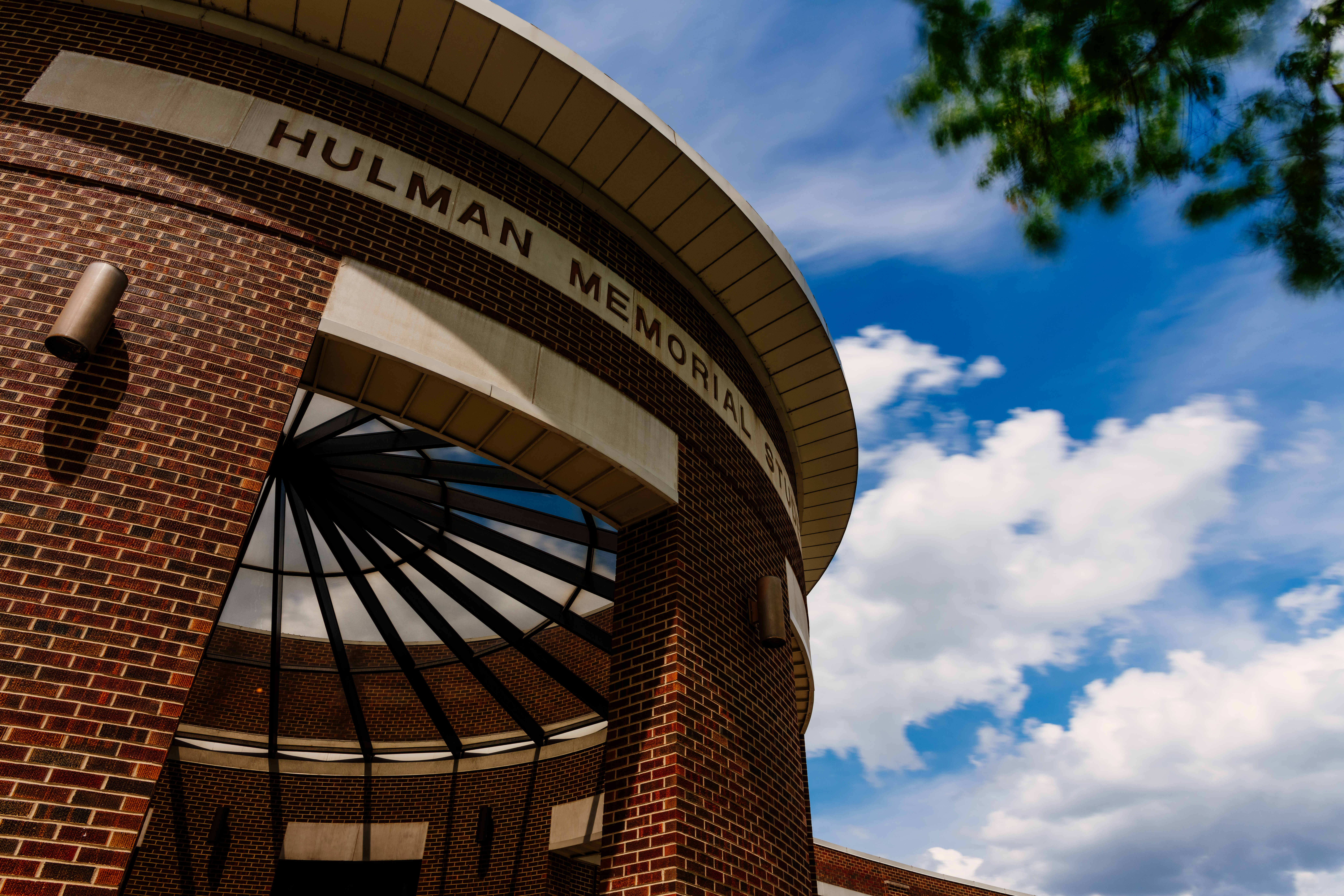 Exterior view of Hulman Memorial Student Union brick building under a blue sky with clouds.