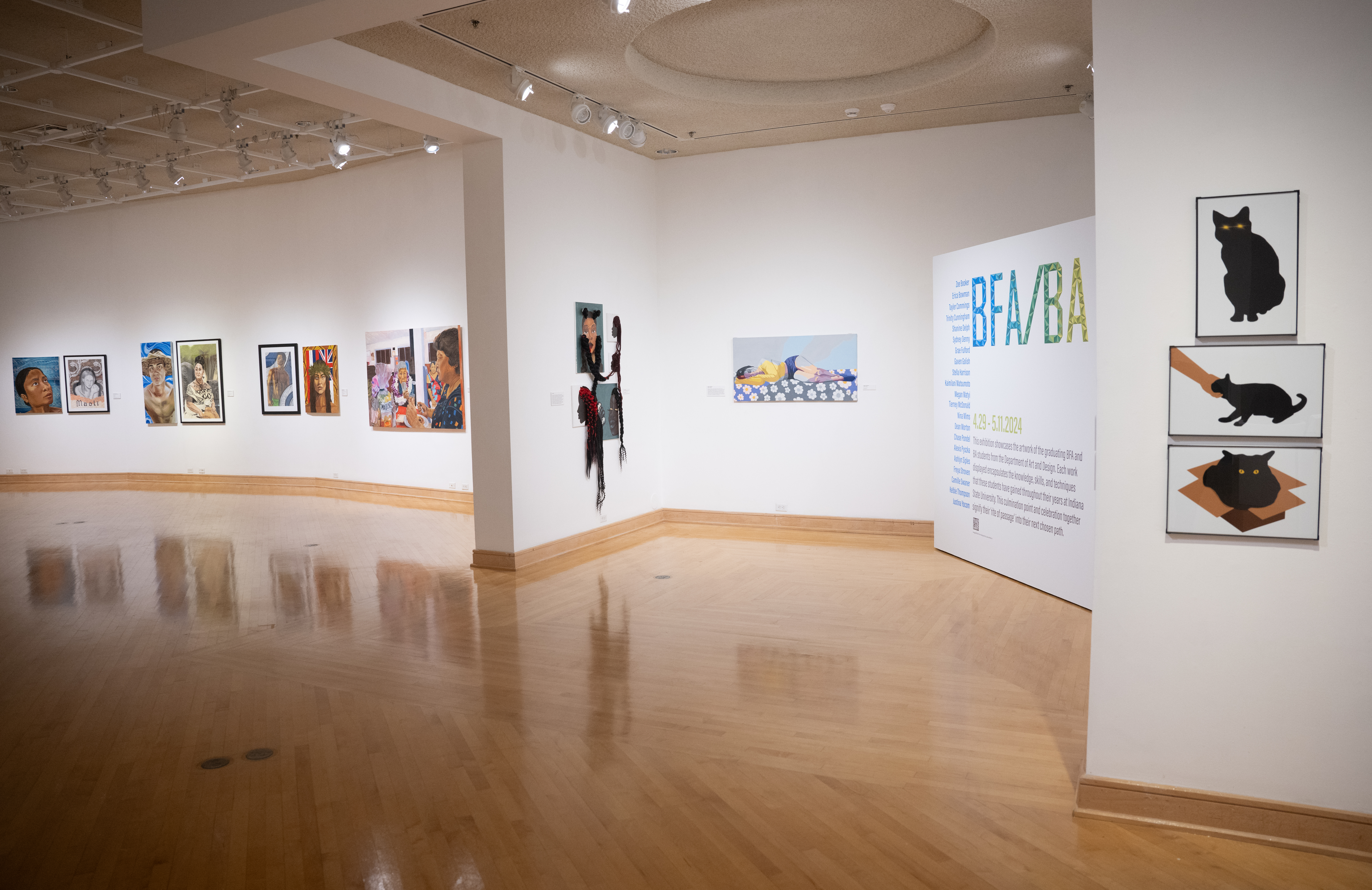 Gallery space with diverse paintings including portraits and an abstract figure, with a large BFA/BA exhibition sign on a white wall.