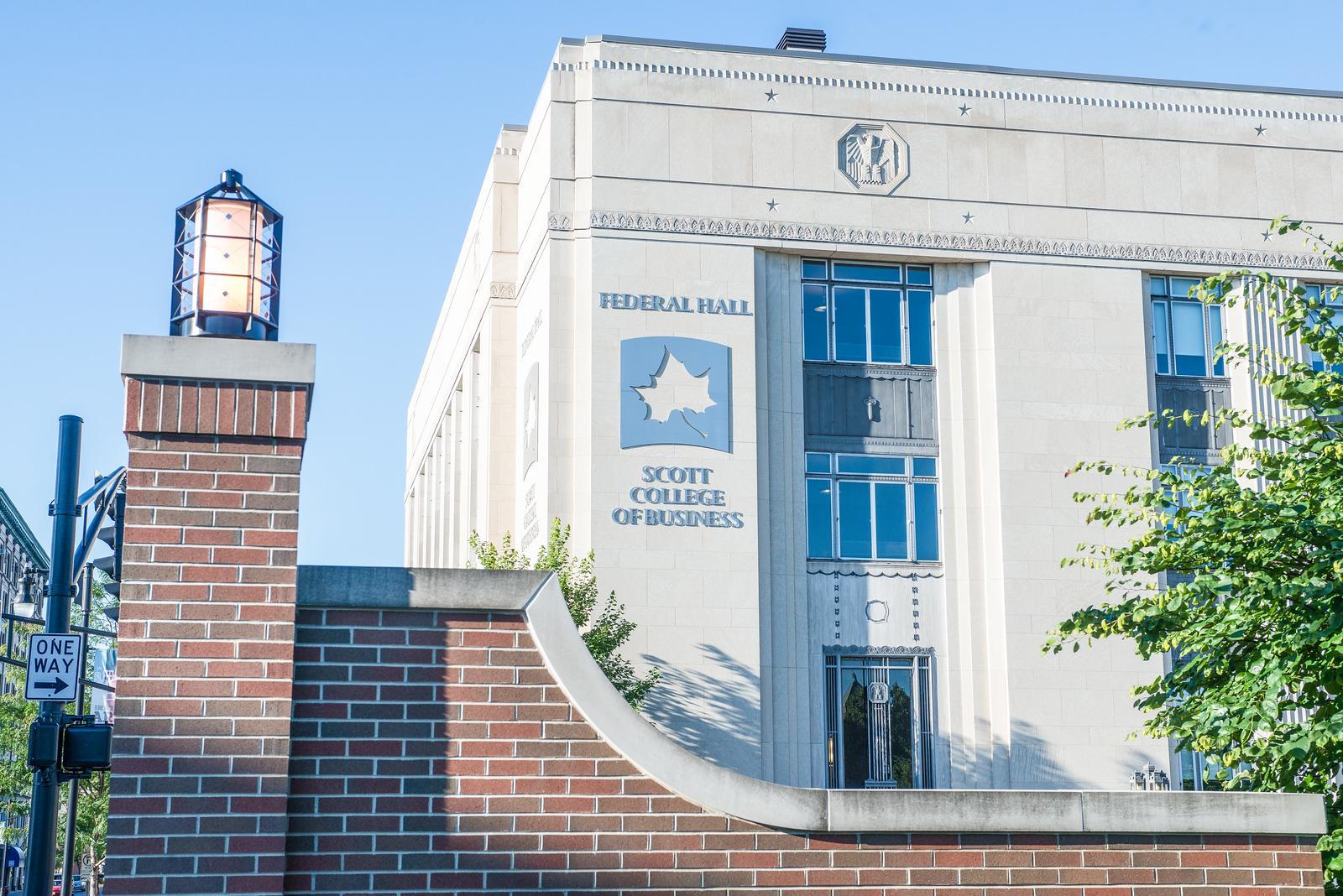 Federal Hall building of Scott College of Business with a brick pillar and a street sign showing one way arrow on a clear sunny day.