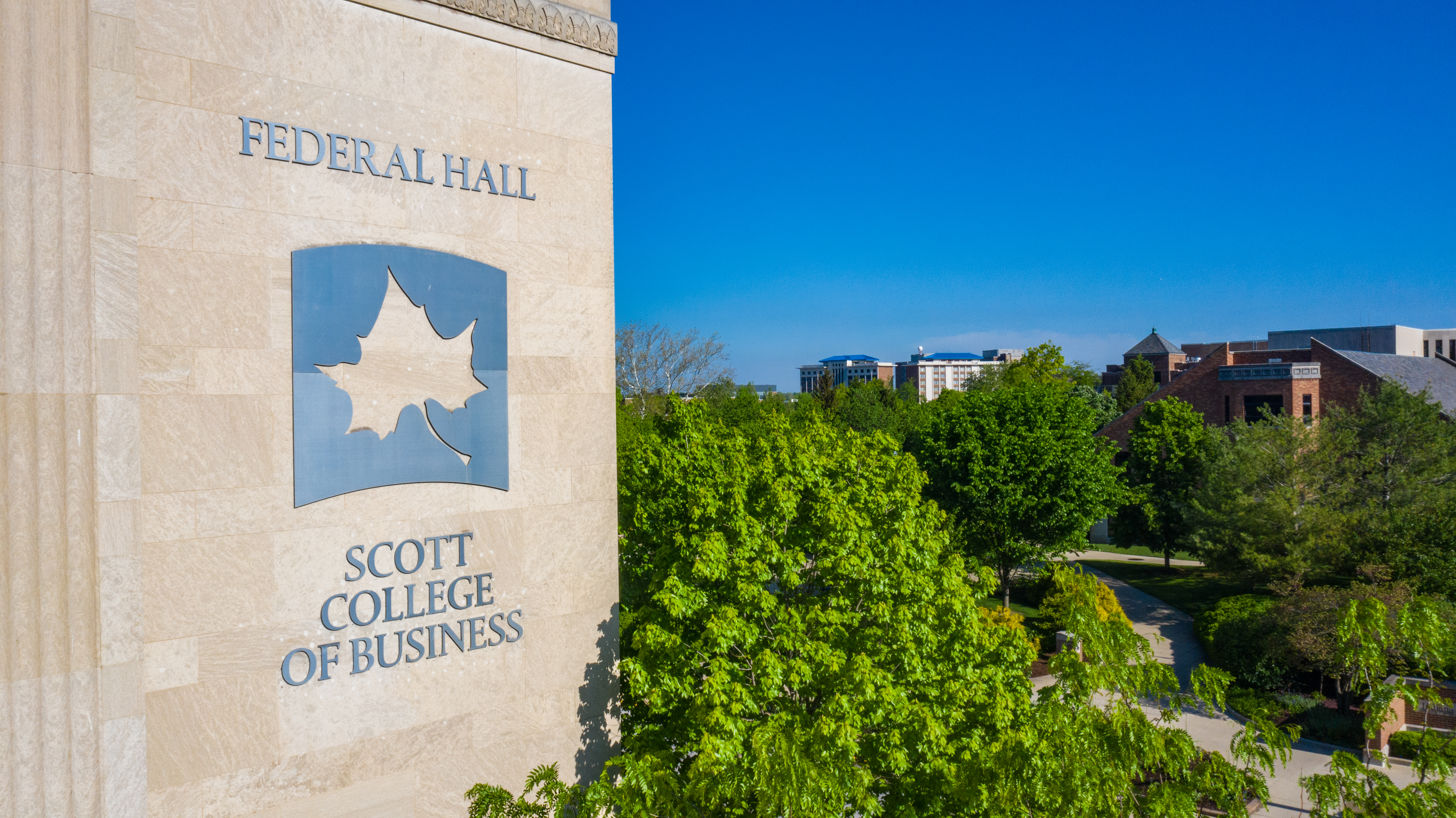 Federal Hall building with Scott College of Business signage next to green trees and a clear blue sky on Indiana State University campus.