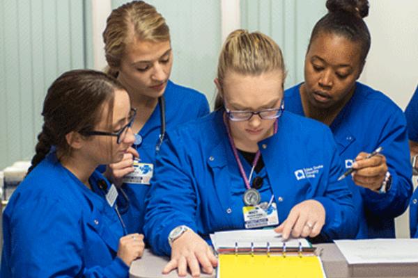 A group of six nursing students all look over a chart